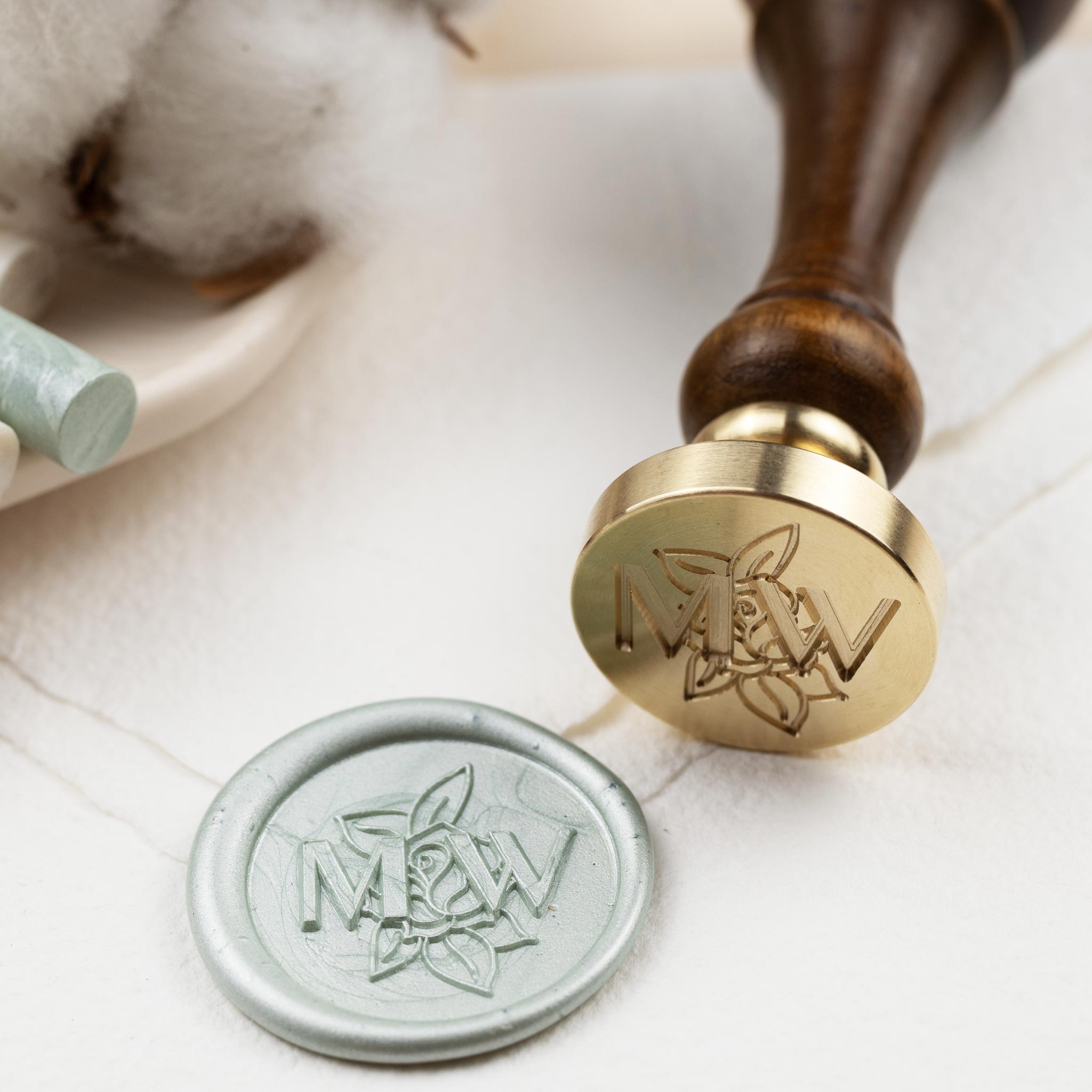 Siegelstempel mit gravierten Initialen im Hintergrund auf dem Siegeleine Rose