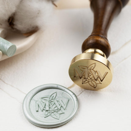 Siegelstempel mit gravierten Initialen im Hintergrund auf dem Siegeleine Rose